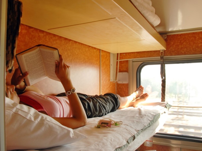 Eine Frau liest ein Buch im Schlafwagen eines Zuges.