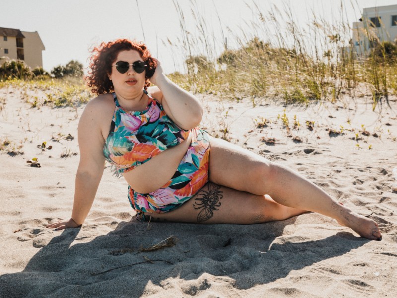 Eine Plus-size-Frau im Bikini an einem Strand.