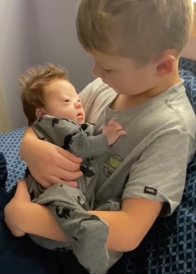 Ein junge hält seinen neugeborenen Bruder in den Armen.