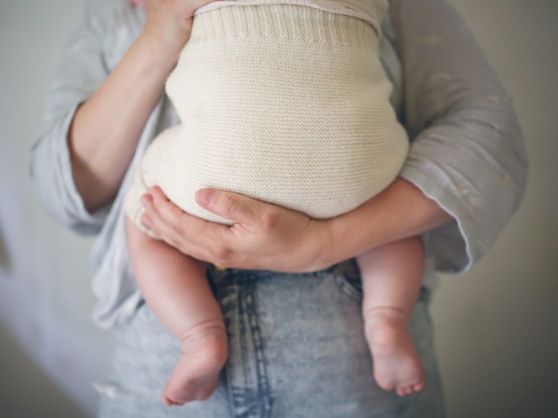 Eine Mutter hält ihr gewickeltes Baby im Arm.