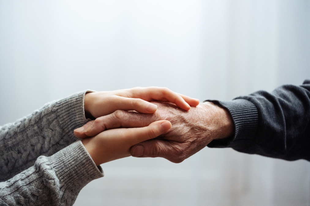 Eine Nahaufnahme von einem alten Mann, der die Hand einer jungen Frau hält.